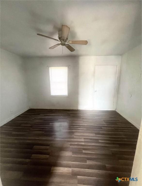 empty room with wood finished floors, a ceiling fan, and baseboards