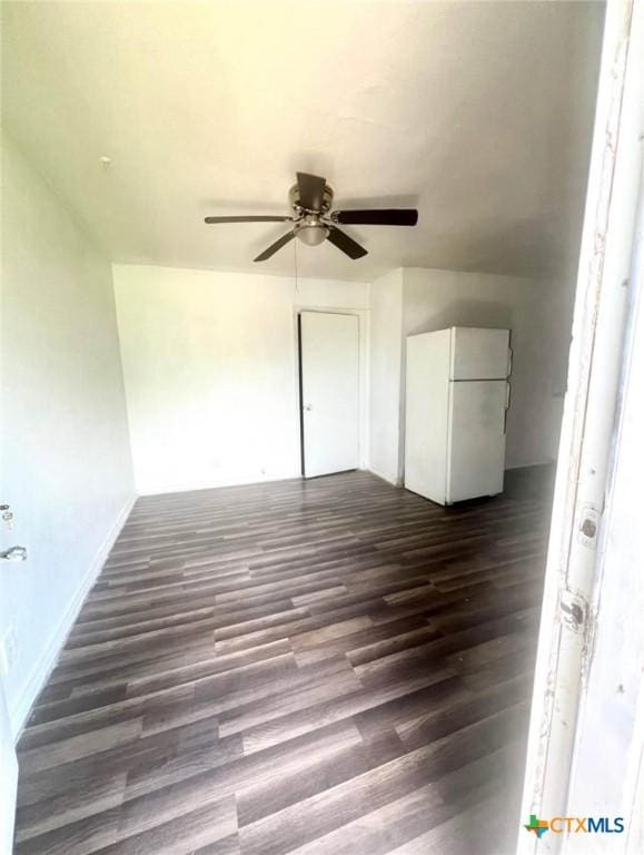 interior space featuring dark wood-type flooring, a ceiling fan, and freestanding refrigerator