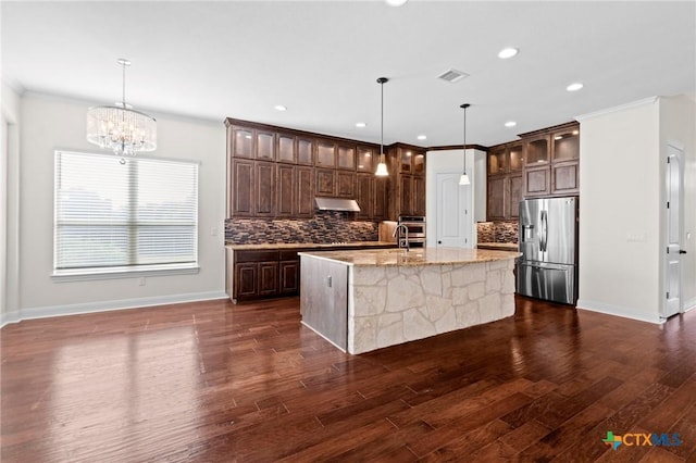 200 Tate Ln, Round Rock, TX 78626 - kitchen with stainless steel appliances, under cabinet range hood, a center island with sink, tasteful backsplash, and light stone counters