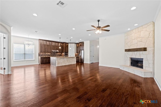 200 Tate Ln, Round Rock, TX 78626 - unfurnished living room featuring a stone fireplace, ceiling fan, dark wood-type flooring, a chandelier, and recessed lighting