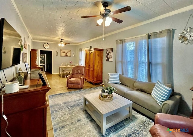 living area with light wood-type flooring, crown molding, baseboards, and ceiling fan