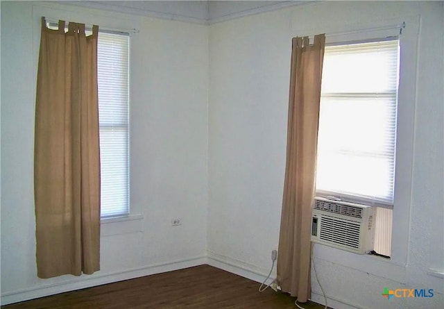 spare room featuring dark wood-style floors, plenty of natural light, cooling unit, and baseboards