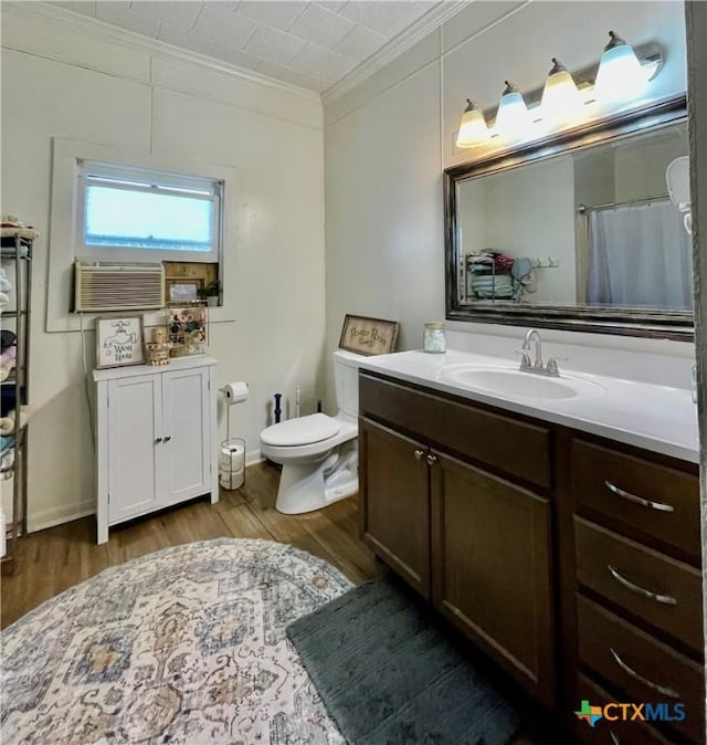 bathroom with cooling unit, toilet, wood finished floors, vanity, and ornamental molding