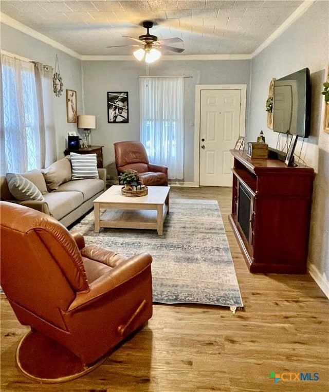 living area with light wood-style floors, ceiling fan, crown molding, and a wealth of natural light