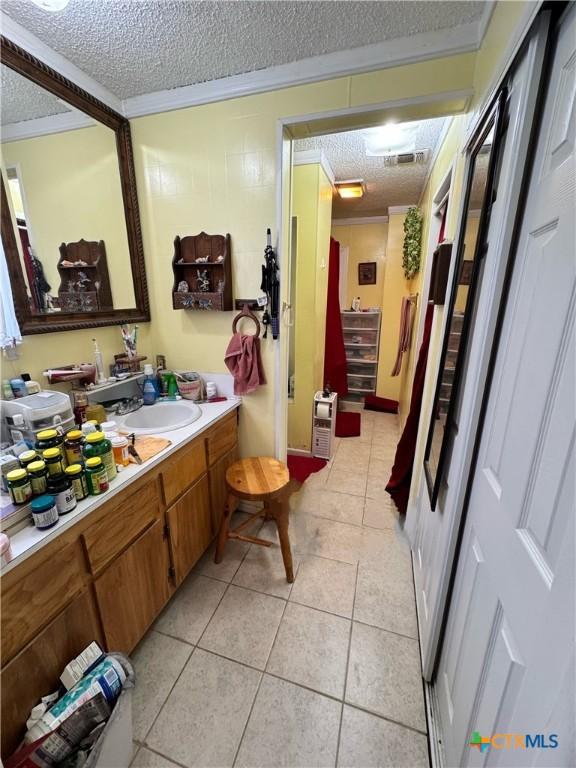 bathroom featuring a textured ceiling, tile patterned floors, vanity, and crown molding