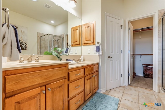 bathroom with tile patterned flooring, vanity, and walk in shower