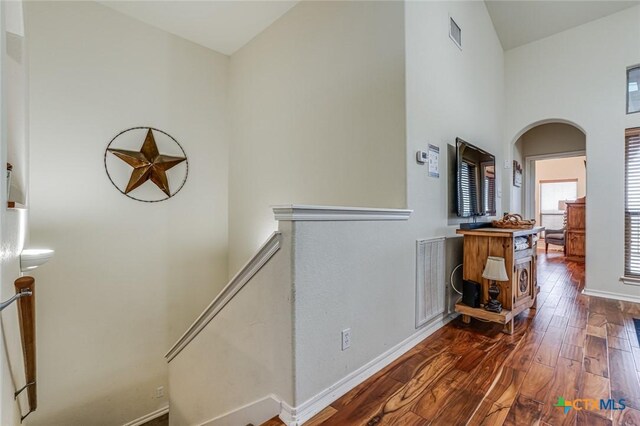 hallway with dark hardwood / wood-style flooring and a towering ceiling