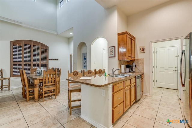 kitchen featuring sink, light tile patterned floors, a breakfast bar area, backsplash, and stainless steel appliances