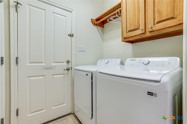 clothes washing area with cabinets, washing machine and dryer, and light tile patterned flooring