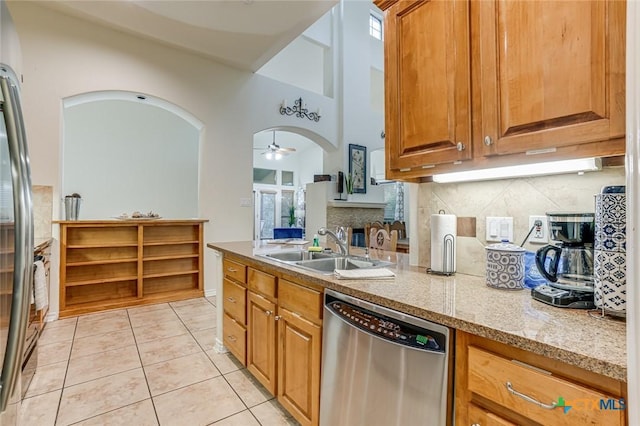 kitchen with sink, light tile patterned floors, ceiling fan, appliances with stainless steel finishes, and light stone countertops