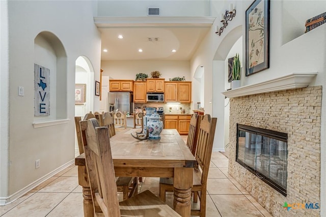 dining area featuring light tile patterned flooring and a stone fireplace