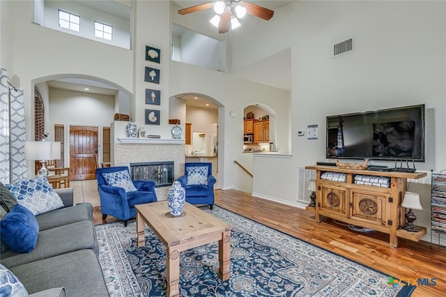 living room featuring light hardwood / wood-style flooring, ceiling fan, and a high ceiling