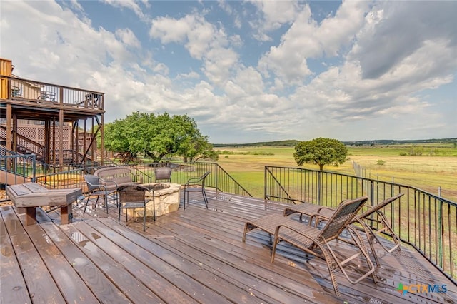 deck with a rural view and a fire pit