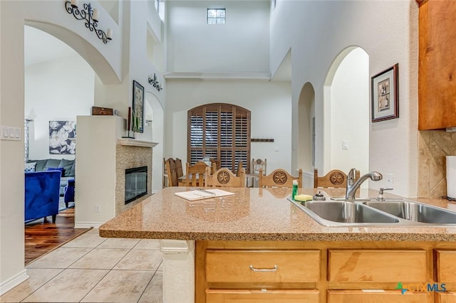 kitchen featuring sink, light tile patterned floors, decorative backsplash, and a high ceiling