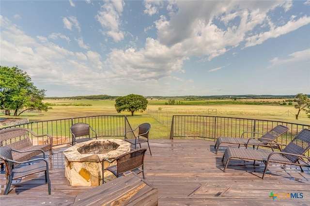 wooden terrace with a lawn, a rural view, and a fire pit