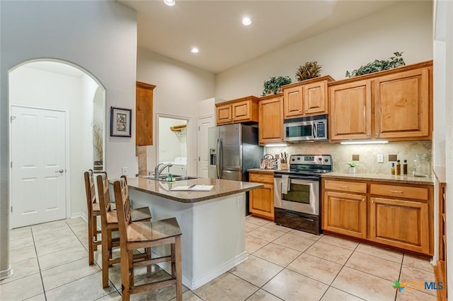 kitchen featuring sink, light tile patterned floors, stainless steel appliances, light stone countertops, and backsplash