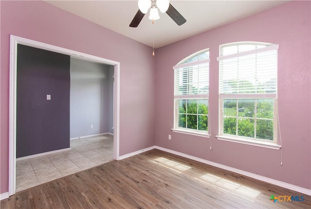 empty room with ceiling fan, wood finished floors, and baseboards