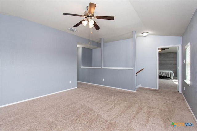 spare room with ceiling fan, visible vents, vaulted ceiling, baseboards, and carpet floors