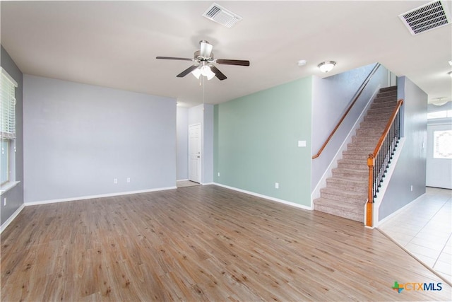 unfurnished living room featuring stairs, visible vents, and wood finished floors