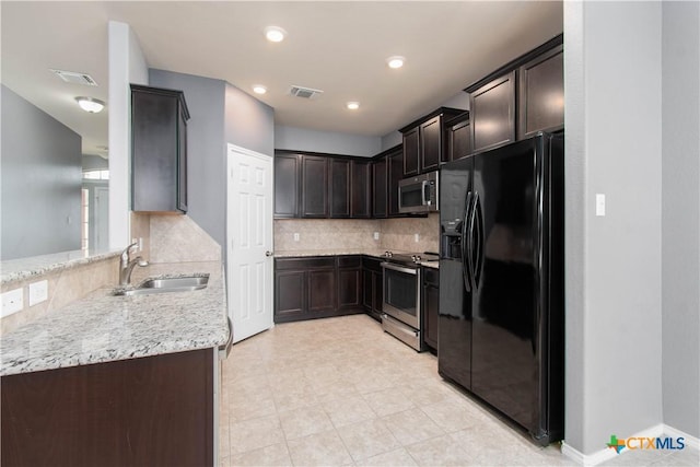kitchen with a sink, visible vents, stainless steel appliances, dark brown cabinetry, and backsplash