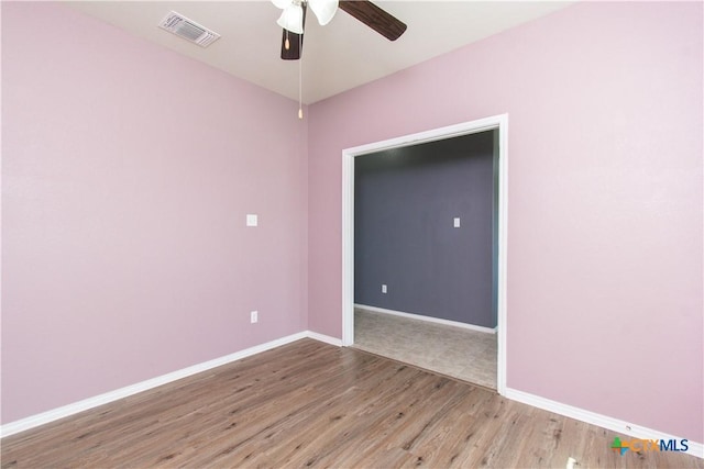 empty room with baseboards, visible vents, wood finished floors, and ceiling fan