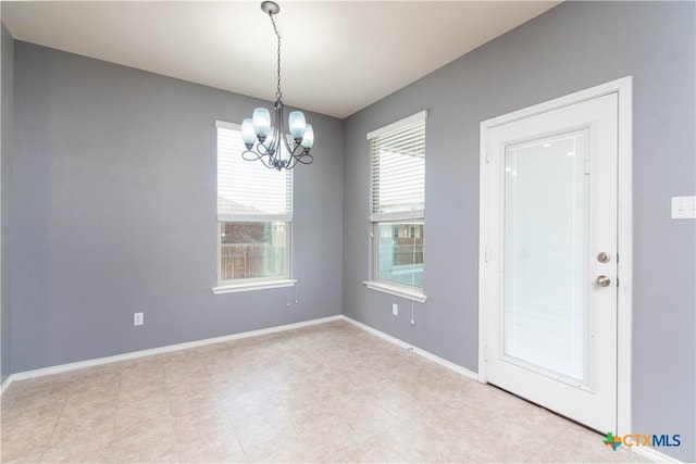 spare room featuring a notable chandelier and baseboards