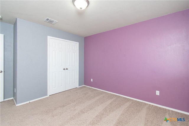 unfurnished bedroom featuring carpet, visible vents, baseboards, and a closet