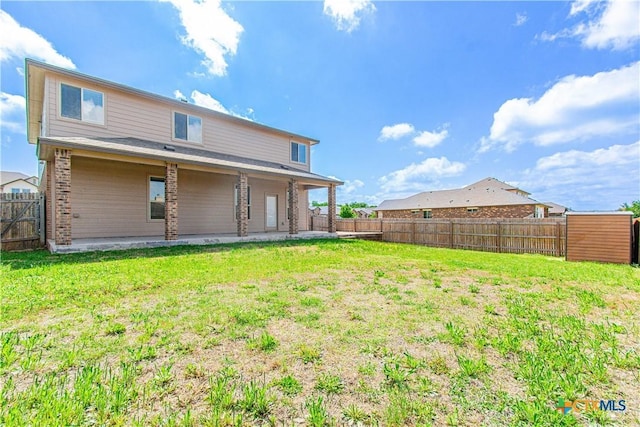 rear view of property featuring a patio, a yard, a fenced backyard, and brick siding