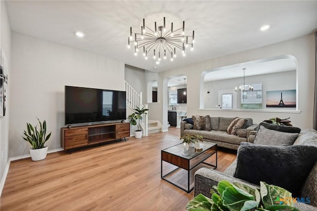 6309 Carriage Pines Dr, Del Valle, TX 78617 - living room featuring light wood finished floors, a chandelier, stairs, track lighting, and arched walkways