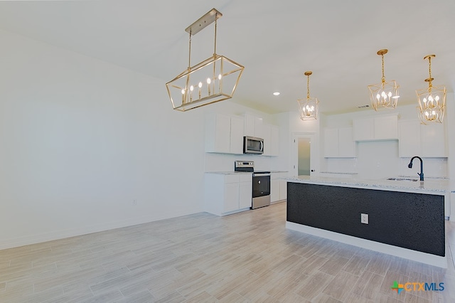 kitchen featuring white cabinets, appliances with stainless steel finishes, hanging light fixtures, and light stone countertops