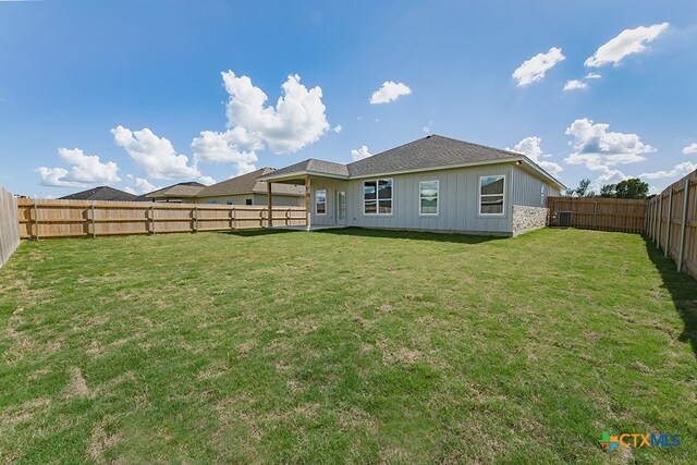 back of house with central AC unit and a lawn