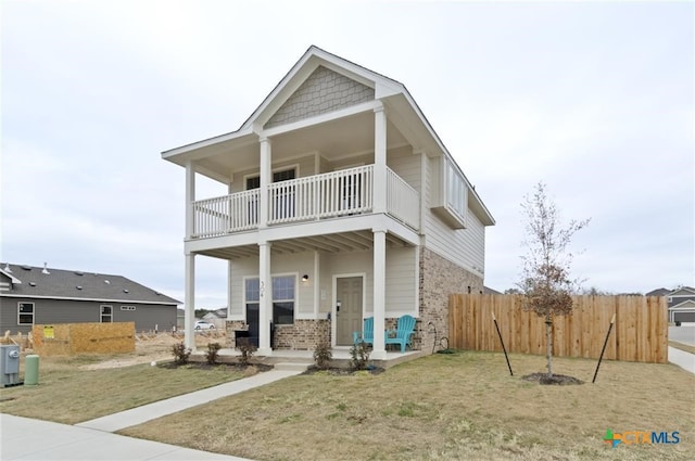 view of front facade with a balcony, covered porch, and a front lawn