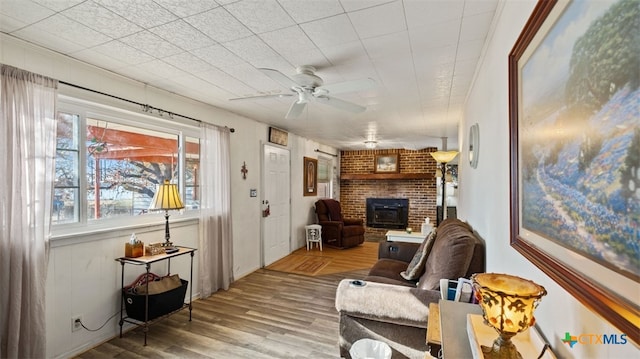 living room featuring hardwood / wood-style flooring, ceiling fan, and a wood stove