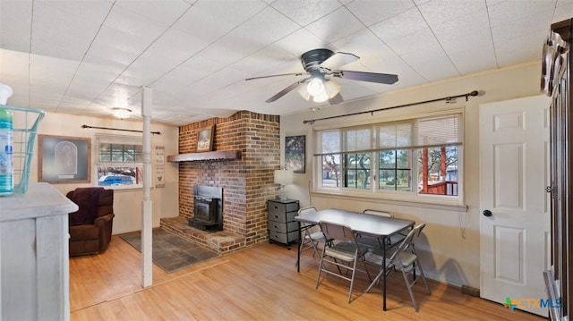 dining space with hardwood / wood-style floors, ceiling fan, and a wood stove