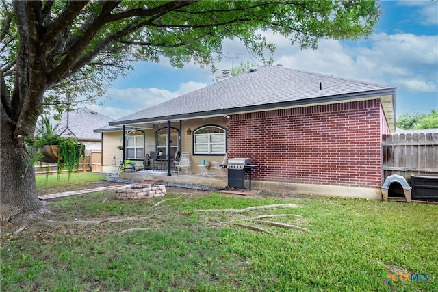 back of house featuring a patio, fence, a lawn, and brick siding