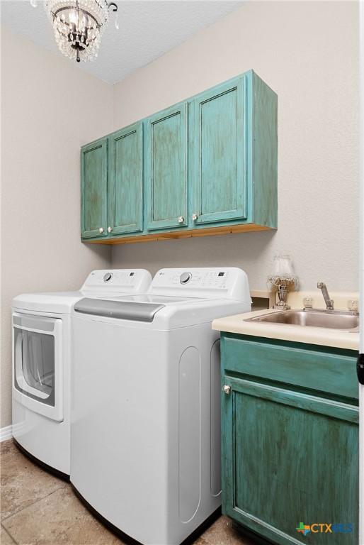 laundry room with a sink, washing machine and dryer, cabinet space, and a notable chandelier