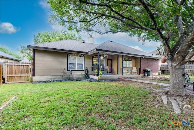 rear view of property featuring a yard and fence