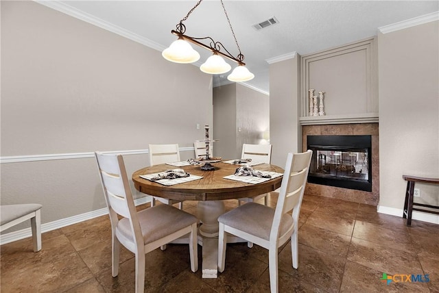 dining area with ornamental molding, a multi sided fireplace, visible vents, and baseboards