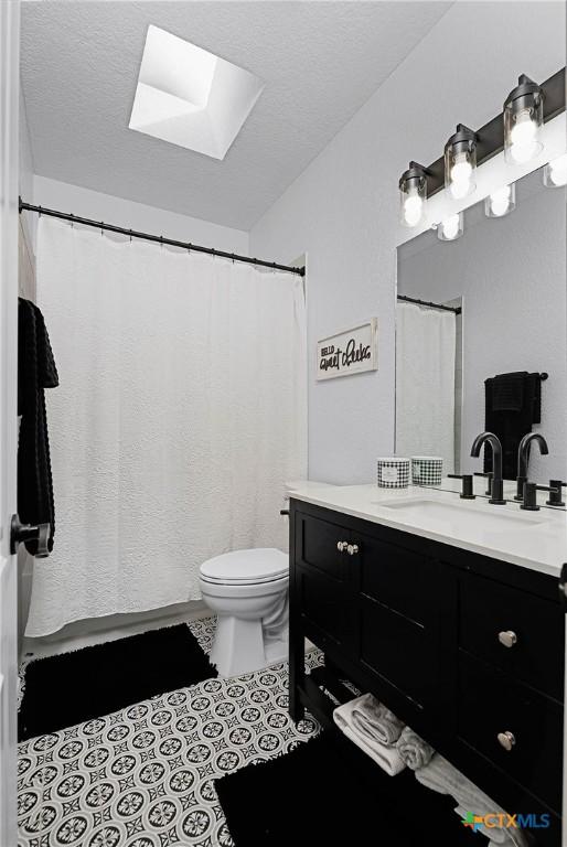 full bathroom featuring a textured ceiling, vanity, toilet, and tile patterned floors