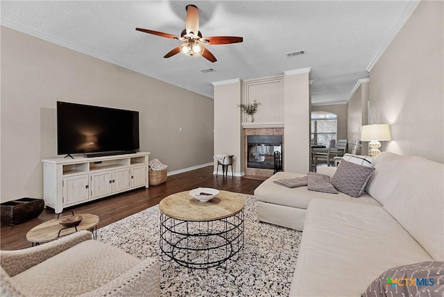 living area with baseboards, visible vents, wood finished floors, crown molding, and a fireplace