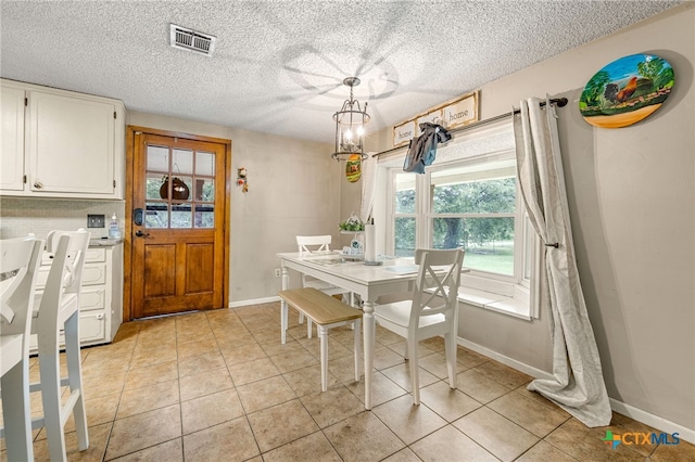 dining space featuring a textured ceiling and light tile patterned flooring