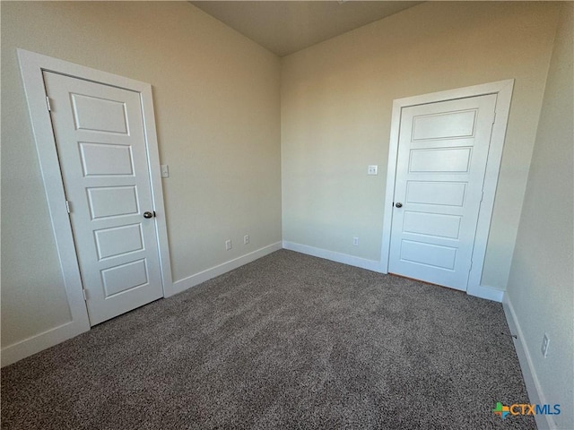 empty room with dark carpet and baseboards