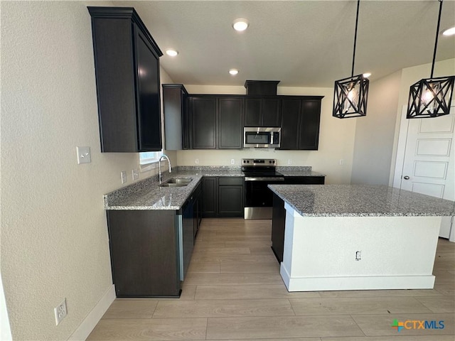 kitchen with a kitchen island, pendant lighting, stainless steel appliances, and a sink