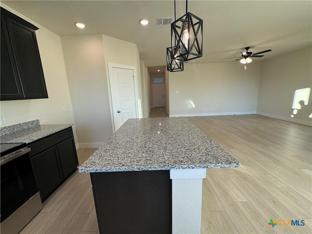 kitchen featuring a center island, visible vents, stainless steel electric range oven, and hanging light fixtures