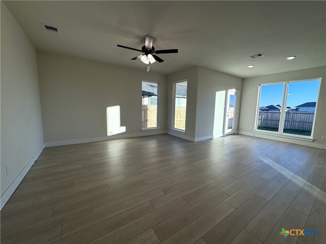 spare room featuring ceiling fan, wood finished floors, visible vents, and baseboards