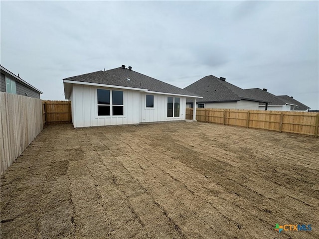 back of property with board and batten siding and a fenced backyard