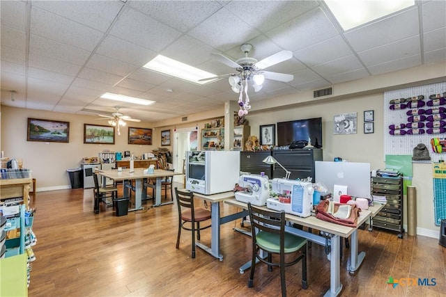 dining area with ceiling fan, a paneled ceiling, wood finished floors, visible vents, and baseboards