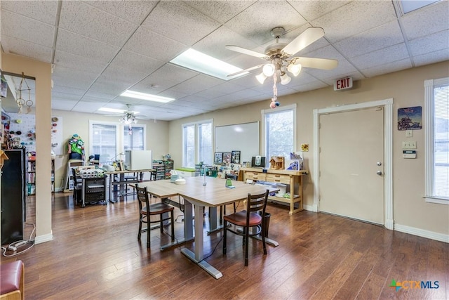 dining room featuring dark wood-style flooring, a drop ceiling, ceiling fan, and baseboards