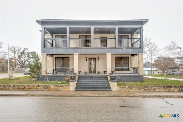 front of property with covered porch, brick siding, and a balcony