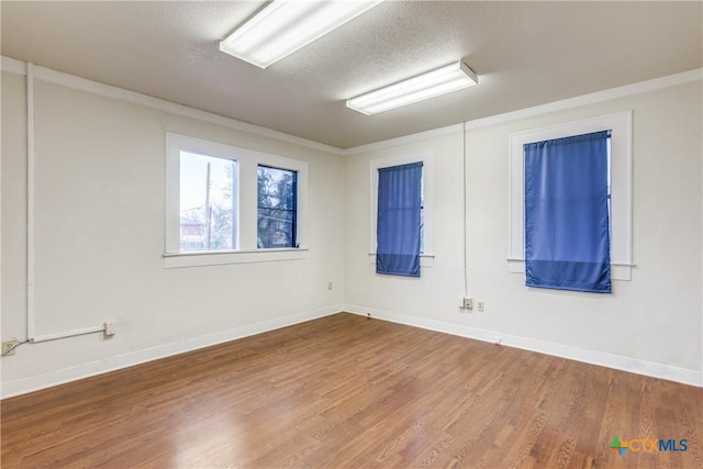 unfurnished room featuring a textured ceiling, baseboards, and wood finished floors